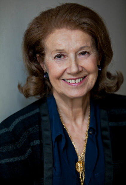 A smiling woman with red hair looks directly into the camera.