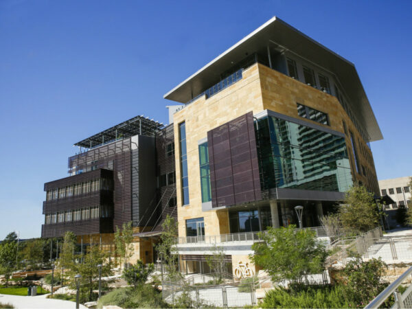 An exterior view of the Austin Central Library. There is landscaping and greenery surrounding the library.