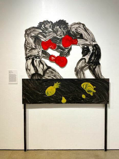 A shaped canvas of two boxers sparring atop a table.