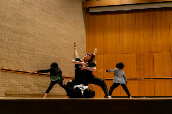 Four movement artists perform on stage.