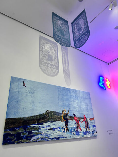 Two papel picados and a large textile piece hang on the wall of a gallery.