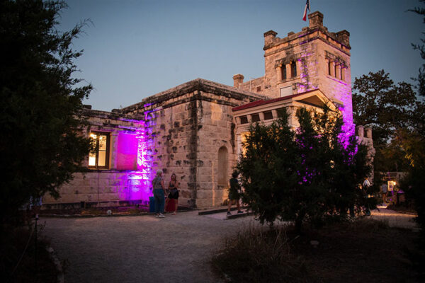 A large castle like structure at dusk with purple lighting.