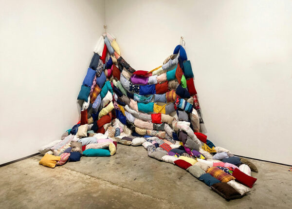 A large textile work fills the corner of a gallery.