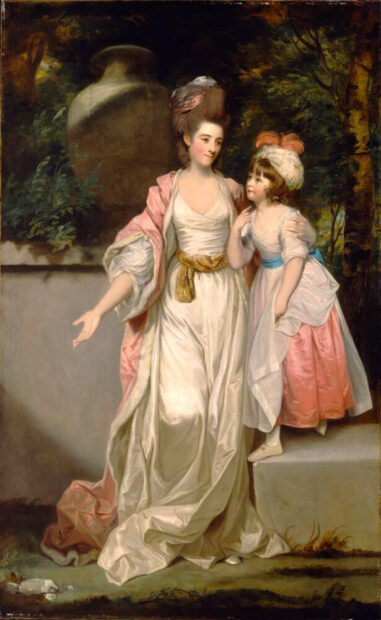 A woman stands next to her daughter wearing a fancy gown.