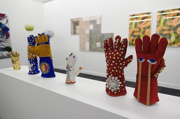 Pairs of bedazzled leather gloves stand upright on a plinth.