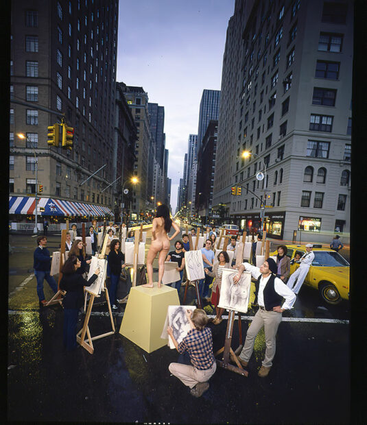 A group of artists stand before the easels on a Manhattan street while a nude model stands on a pedestal.