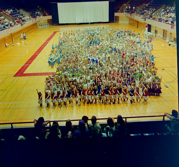 A large group of cheerleaders pose for a photograph on a basketball court.