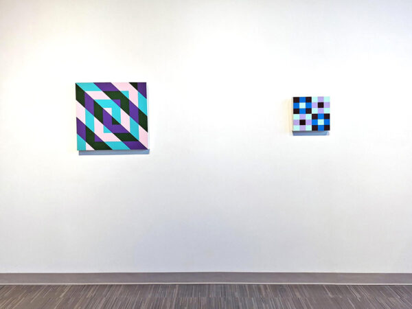 Two colorful abstract paintings hang on the wall of a gallery.