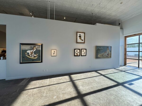 Figurative paintings hang in a gray-walled gallery.