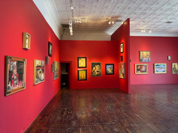 Figurative paintings hang in a red-walled gallery.