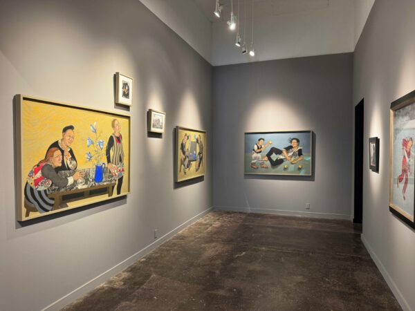 Figurative paintings hang in a gray-walled gallery.