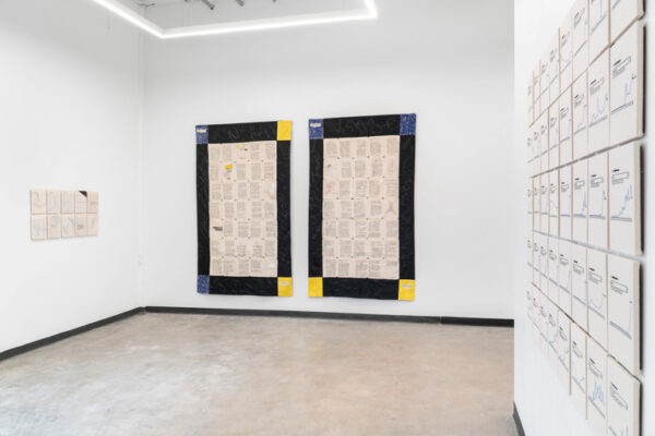 A gallery with two large quilts and a grid of dozens of smaller embroidered works.