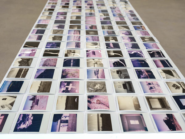 A large table covered with Polaroid images of Marfa and its surroundings.