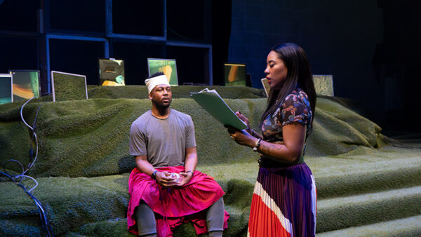 A man and a woman stand on stage rehearsing a play.