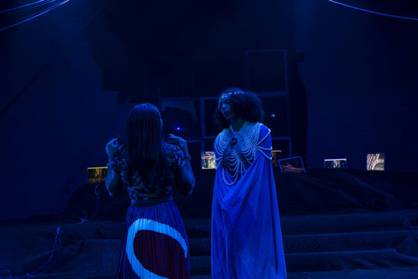 Two actors stand on stage during a rehearsal of a play.