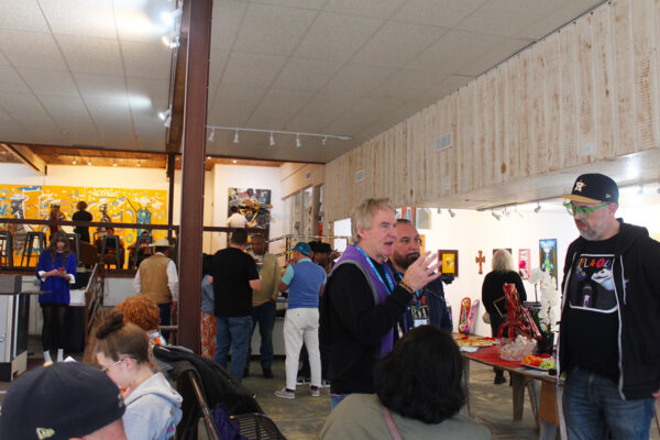 A photograph of people gathered inside an art gallery for an opening reception.