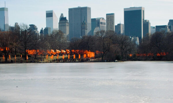 A long line of orange cloths are suspended from gates in Central Park.