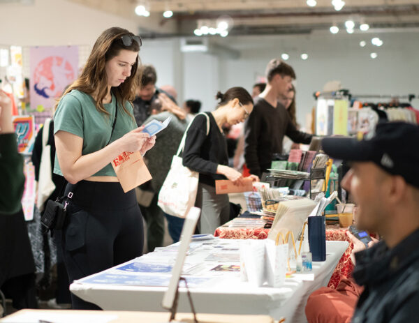A photograph of people looking at books and zines at a book fair.