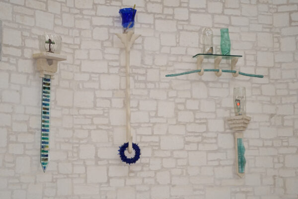 An installation image of a sculptural work by Damion Priour featuring limestone shelves, glass vessels, and found objects.