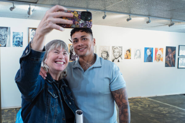 Gallerist Daniel Ceyala takes a photograph with an attendee at Be Free Gallery.