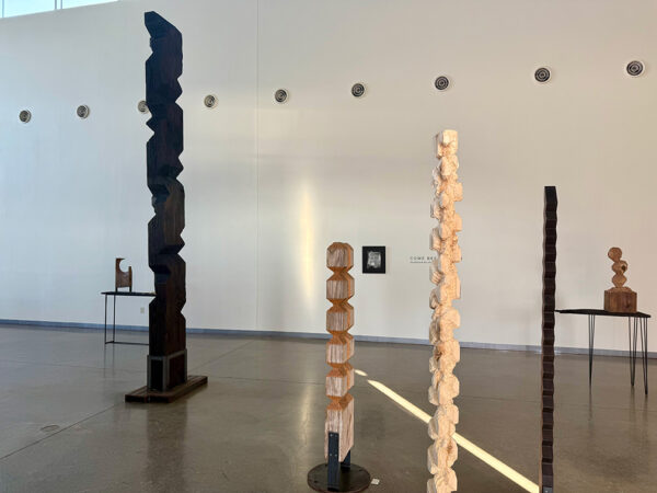 A high-ceilinged gallery with tall, totemic wooden carvings.