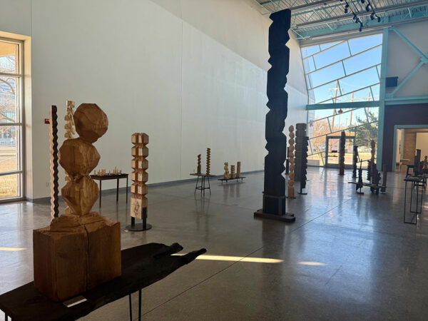 A large gallery with several towering wooden sculptures.