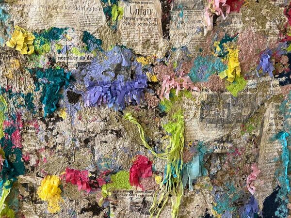 Colorful bits of paper stick out from a collage of newspaper headlines.