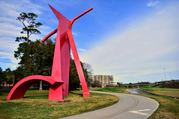 A photograph of a large red abstract sculpture by Mac Whitney.