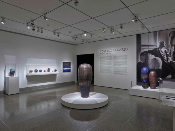 Installation photograph of a ceramics exhibition, featuring multiple works hug on and displayed against walls and plinths.