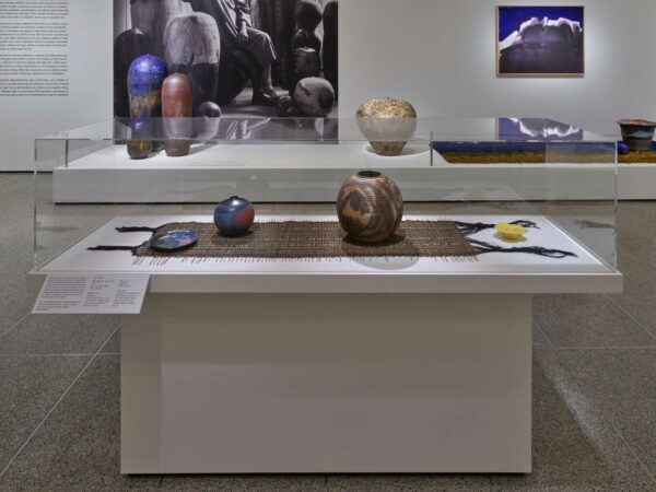 Installation photograph of a ceramics exhibition, featuring multiple works hug on and displayed against walls and plinths.