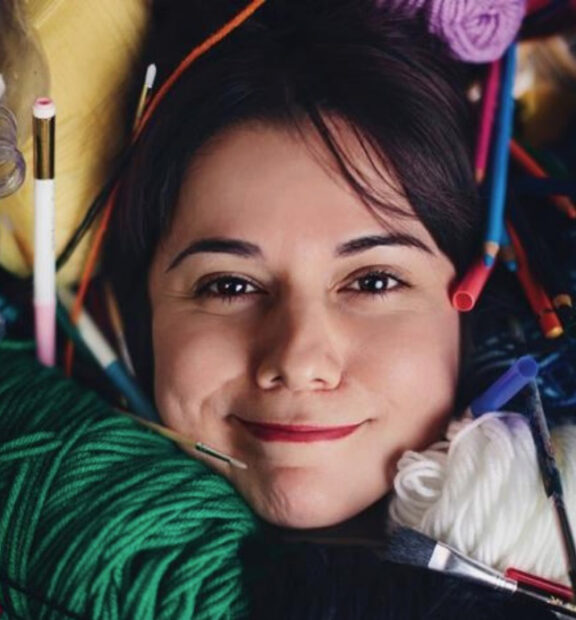 A photograph of artist and arts administrator Mary Cantú with art materials surrounding her face.