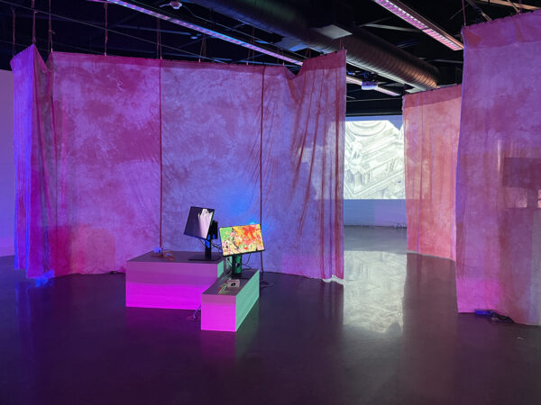 An installation image depicting tv monitors and video projects with hanging curtains dividing the space. 