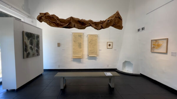 An installation image featuring framed artworks on a white gallery wall.