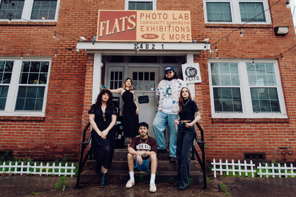 Five people pose on the steps outside of a photo processing lab.