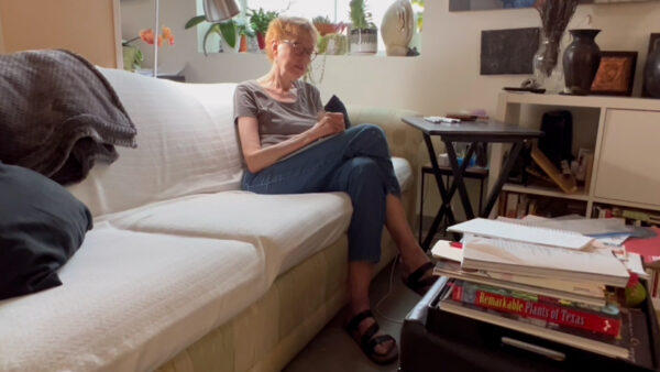 A photograph of an older woman sitting on a couch.