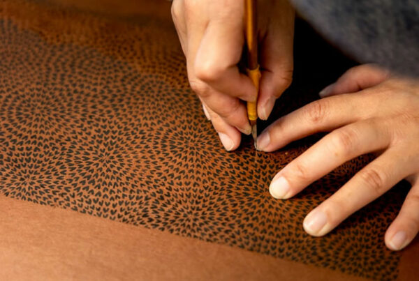 A pair of hands cuts an intricate stencil.