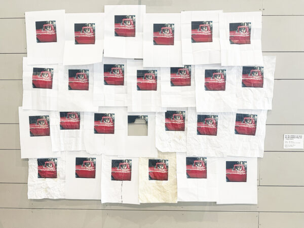 An installation of 24 photographs featuring a pair of children sitting in the front seat of a truck.