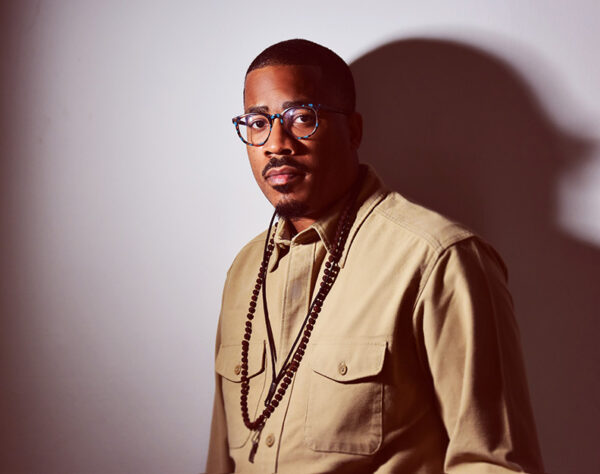 A man in a beige shirt looks directly into the camera.