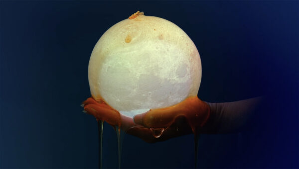 A still image of a hand holding a dripping orb, from a video by Virginia L. Montgomery.