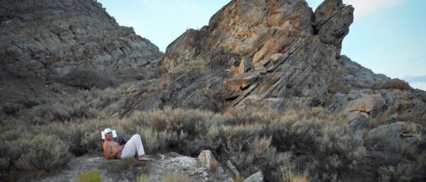 A still image from a video of a performance work by Jorge Rojas, set in a rocky landscape.