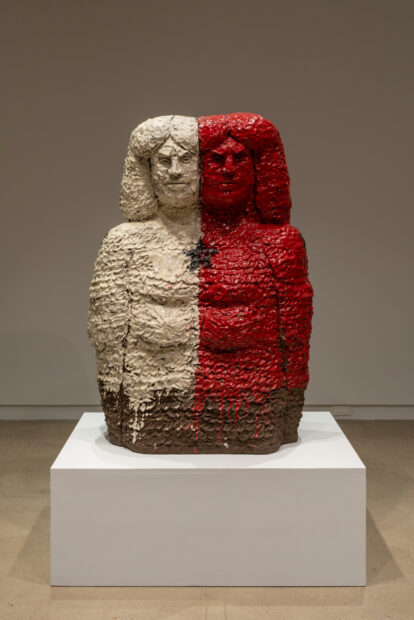 A photograph of a sculpture by Raven Halfmoon, featuring a two-headed figure.
