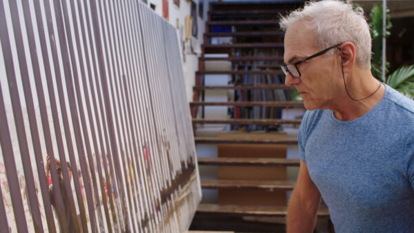 A still image from a video of Richard Misrach looking at a large photograph of the border in his studio.